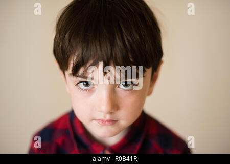 portrait of small lonely sad pensive caucasian boy with big eyes in plaid shirt Stock Photo
