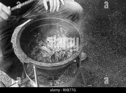 Person is cooking some goulash in a big metal pan with gas heater. Stock Photo