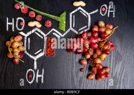 resveratrol rich food, red grape and green aloe slices, goji, peanuts, cranberry, strawberry, formula on the black wooden background, space for text Stock Photo