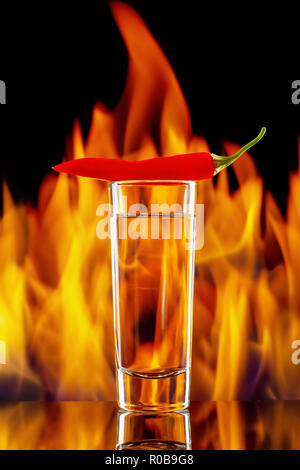 tequila or vodka shot with chili pepper on fire background Stock Photo
