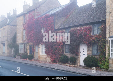 Sheep street cottages covered in Boston Ivy in the early morning autumn fog, Stow on the Wold, Gloucestershire, Cotswolds, England Stock Photo
