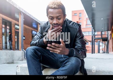 Close up of dark-skinned man looking at mobile phone screen. Stock Photo
