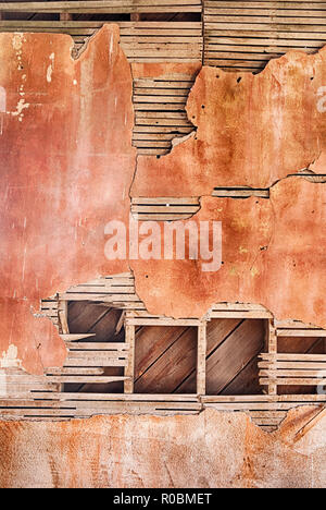 An architectural background results from the cracked plaster and lathe on an old red wall in a ghost town schoolhouse in Govan, Washington. Stock Photo