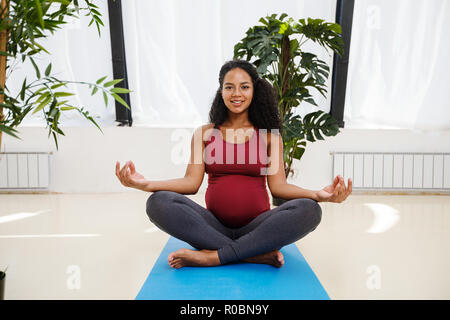 Young beautiful pregnant female meditating in studio Stock Photo