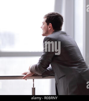 Businessman standing near the window and looking into it Stock Photo