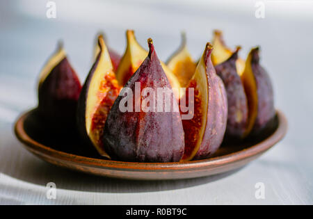 Ripe figs in a plate on a white wooden background. Treatment of anemia. Potassium for the heart. Stock Photo