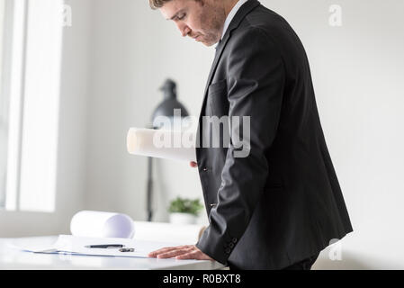Businessman in business suit holding documents working at the plan of a project in the office. Stock Photo