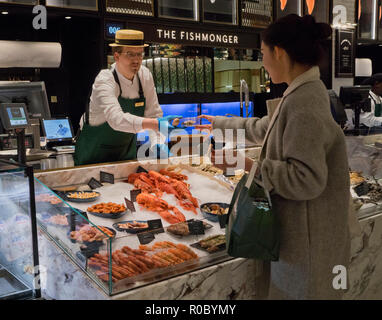 Customer at the fishmonger food counter at Harrods luxury department store. London, England,UK Stock Photo