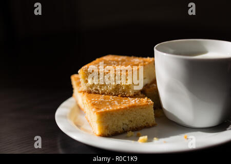 Close-up view of fresh baked corn bread with cheese and cup of yogurt in white plate on wooden table Stock Photo