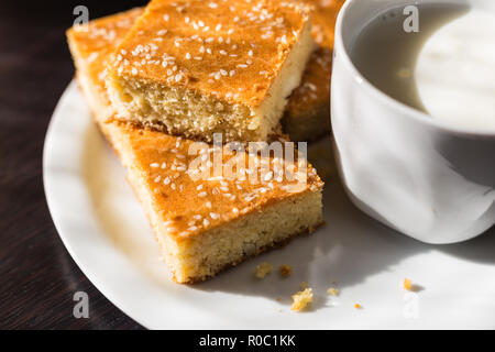 Close-up view of fresh baked corn bread with cheese and cup of yogurt in white plate on wooden table Stock Photo