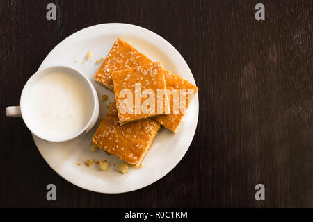 Top view of fresh baked corn bread with cheese and cup of yogurt in white plate on wooden table Stock Photo