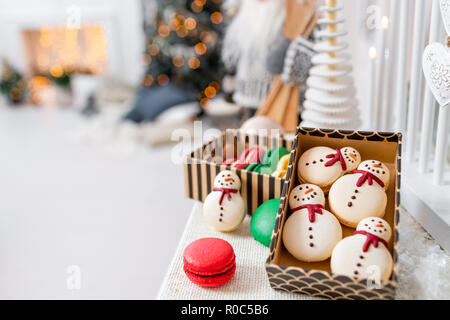Variety of sweet macaroons in carton box. Cookie in the form of a snowman. Merry Christmas card. New year mood. lights of garland bulbs Stock Photo