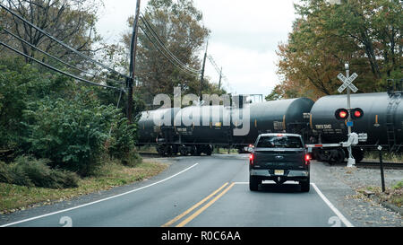 New Jersey, USA: A vehicle stops on an automatic traffic light controlled road railway crossing, or level crossing to allow a goods train to pass. Stock Photo