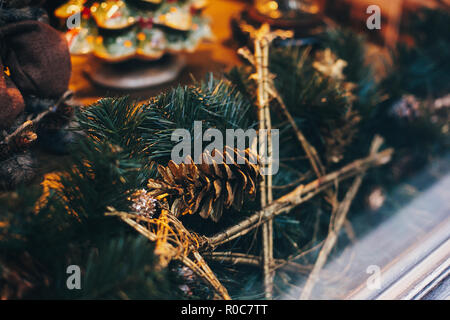 Stylish christmas street decor, golden star ornaments and pine branches with lights in window in european city. Festive decorations and illumination i Stock Photo