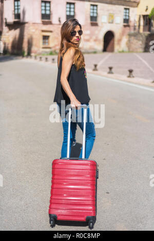 Full length portrait of a woman traveling with trolley. Focus on trolley. Stock Photo