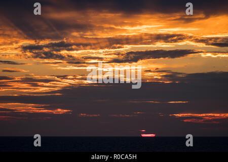 Sun setting through clouds and crepuscular rays seen from L'Etang du Nord in the Magdalen Islands, Quebec, Canada. Stock Photo