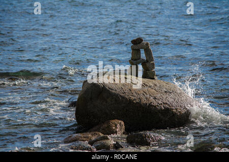 Water splashing up on an Inuksuk in Stanley Park's English Bay, Vancouver, BC, Canada Stock Photo