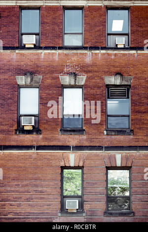 Old red brick wall with rectangle windows and air conditioners mounted in Montreal, Canada Stock Photo