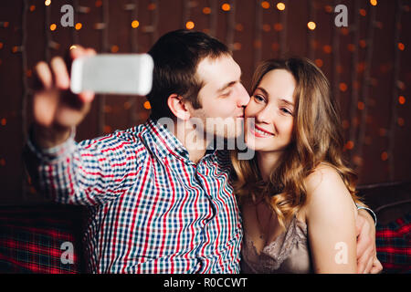 Happy and positive couple making self portrait in decorated for Christmas studio. Stock Photo