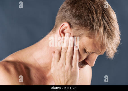 Man has a sore ear. Man suffering from otitis on blue background Stock Photo