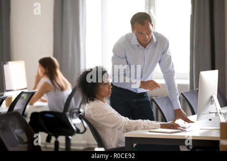 Male caucasian mentor explaining female african intern online ta Stock Photo