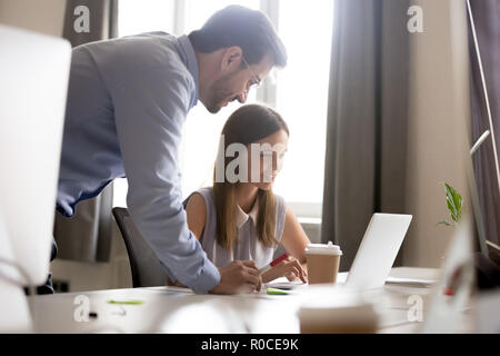 Smiling intern listening to friendly mentor explaining online wo Stock Photo
