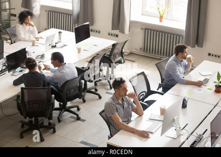 Diverse office workers using computers in modern corporate space Stock Photo