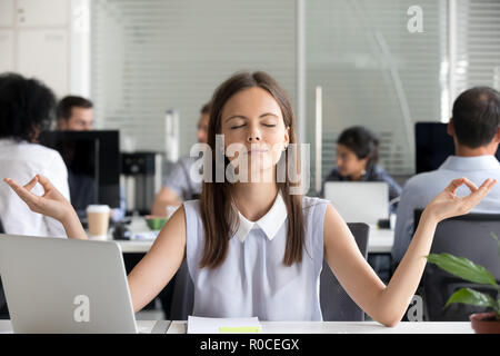 Mindful millennial girl meditating in office taking break for me Stock Photo