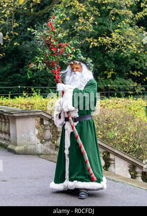 UK, Market Bosworth, Victorian Christmas Fair - December 2015: Father Christmas robed in green, masked and carrying holly branches Stock Photo