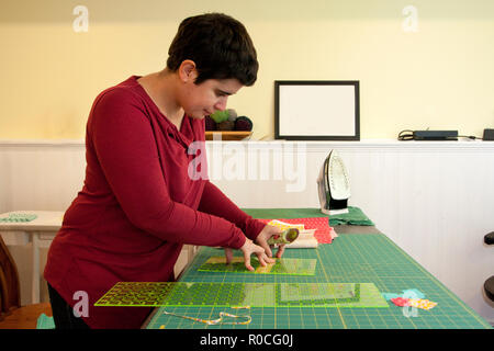 Woman using a fabric cutter and measuring tools to make small strips Stock Photo