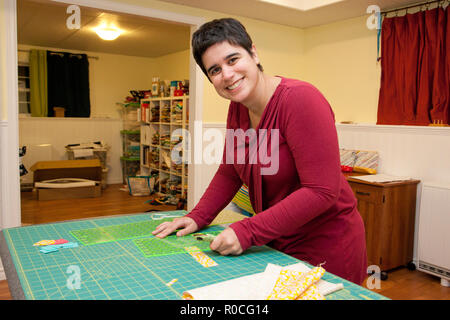 Smiling person working with a fabric grid and cutter in their craft room Stock Photo