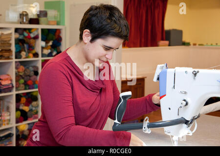 Woman in her sewing studio using a long arm machine working on a project Stock Photo