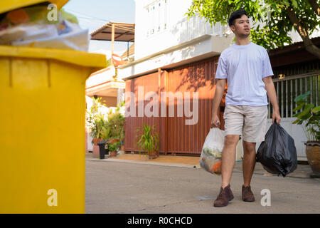 Young Asian man taking out the garbage at home  Stock Photo