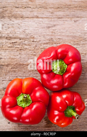 three red bell peppers on rustic wooden table Stock Photo - Alamy
