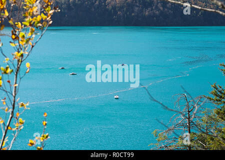 View from the path around the Lake Alpsee, Schwangau, Germany, to the turquoise-coloured lake with pedal boats on it, on a warm sunny day in autumn. Stock Photo