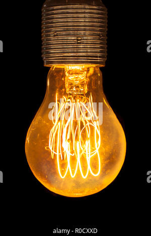 Vintage electric yellow light bulb  glowing in the dark Stock Photo