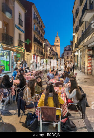 Students at a cafe at night on Calle Rúa Mayor looking towards the tower of the Old Cathedral, Salamanca, Castilla y Leon, Spain Stock Photo