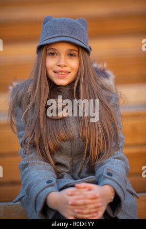 Photo of girl in gray coat sitting on wooden bench Stock Photo