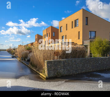Modern geometric family houses along a river in winter with snow and ice, Groningen, Netherlands Stock Photo