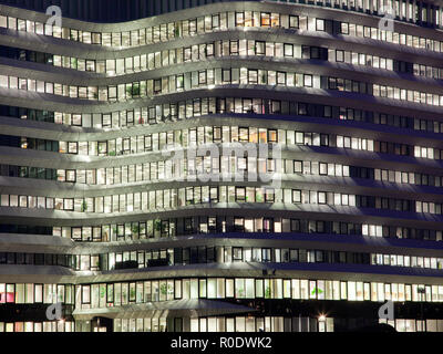 Long Working Hours in an Office Building with Lights at Night in the City with People at Work Stock Photo