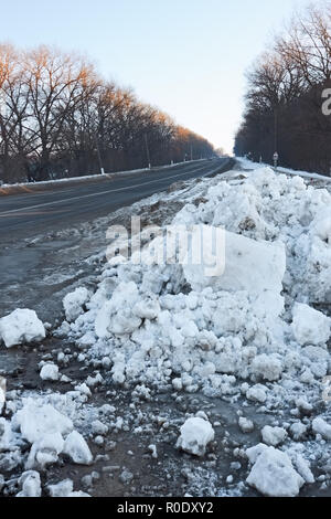 Big snow hummock on the roadside during sunset in winter evening Stock Photo