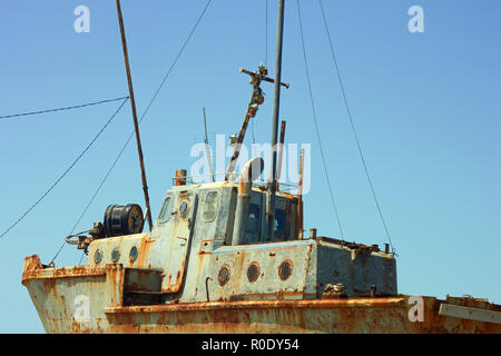 Old rusty small ship against a cloudless sky Stock Photo