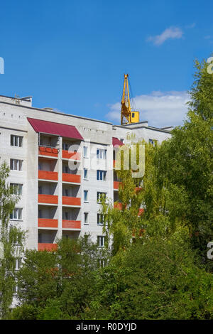Typical modern residential building in the park area. Seen in the background is construction crane Stock Photo