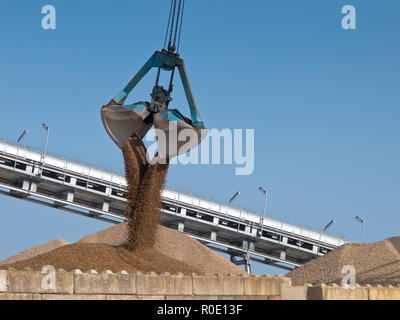 Excavator is releasing a scoop of sand in a silo Stock Photo