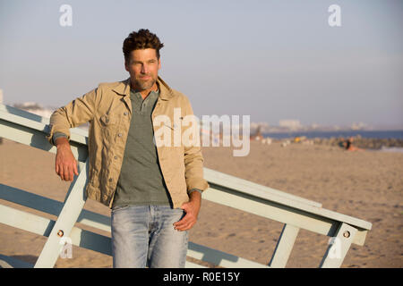 Three-quarter Length Portrait of Mid-Adult Man in Casual Clothes Leaning against Railing at Beach Stock Photo