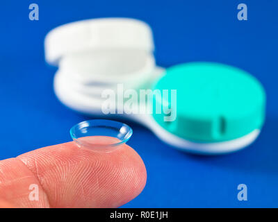 Contact lens on finger tip wit blue background Stock Photo