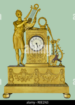 Antique mantel clock of golden musician statue playing harp, on isolated green background with clipping path. Stock Photo