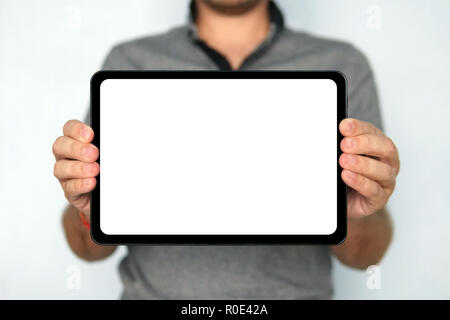 Young man holds a touch pad tablet on isolated white background. Large-size digital tablet with white screen is held by the man on the blurred backrou Stock Photo
