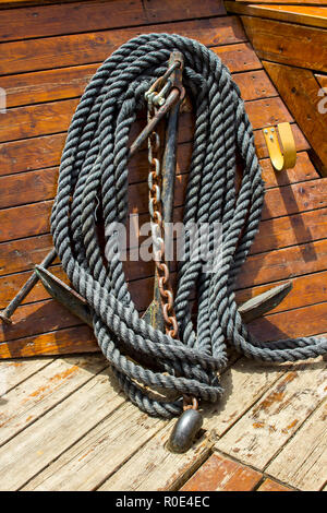 A small anchor, chain and rope stowed safely and neatly  on a traditional wooden tourist boat on the Sea of Galilee in Israel Stock Photo