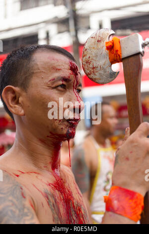 PHUKET TOWN, THAILAND, OCTOBER 09, 2016 : Taoist devotees self harming with an axe for purification during vegetarian festival in Phuket town, Thailan Stock Photo